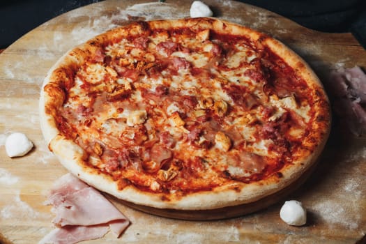 A freshly baked pizza topped with savory ham and gooey cheese rests on a rustic wooden cutting board.