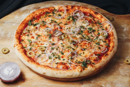 Delicious pizza topped with onions and olives, resting on a rustic wooden cutting board.