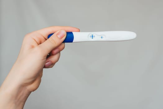 positive pregnancy test in the hands of a girl close-up