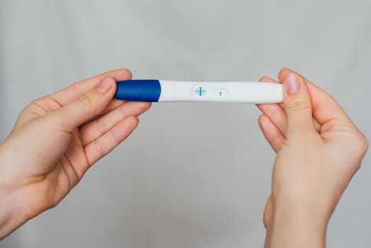 positive pregnancy test in the hands of a girl close-up