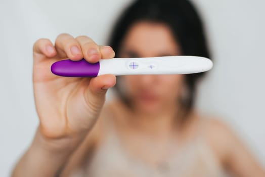 positive pregnancy test in the hands of a girl on the background of her face
