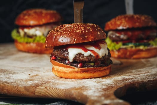 Juicy burgers resting on a wooden cutting board beside a sharp knife, awaiting the sizzle of the grill.