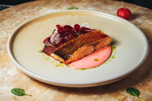 A plate showcasing a vibrant ensemble of juicy salmon fillet and roasted beetroot slices, artistically presented.