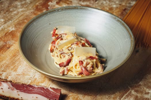 A bowl of pasta topped with juicy meat and accompanied by a slice of freshly baked bread sitting on a table.