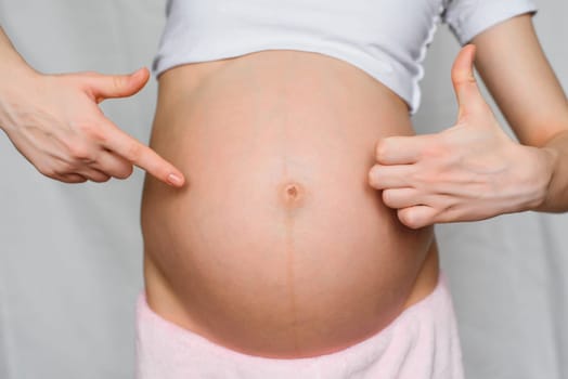 pregnant girl makes a gesture class is a hands on background belly