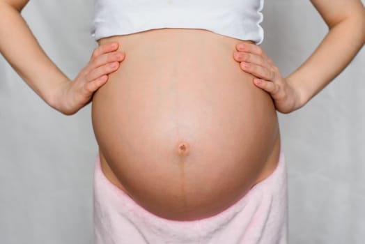 belly of a pregnant girl with her hands close-up