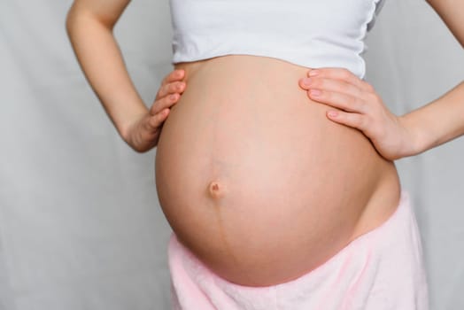 belly of a pregnant girl with her hands close-up