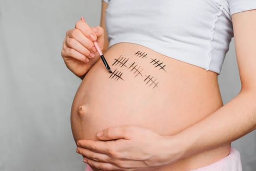 pregnant girl paints pregnancy term on her belly closeup
