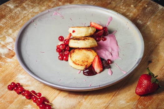 A plate piled high with fluffy pancakes topped with a vibrant assortment of freshly sliced strawberries.