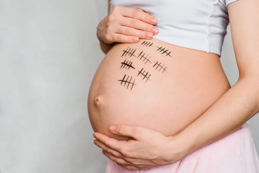 pregnant girl hugs her stomach with a term of pregnancy drawn on it
