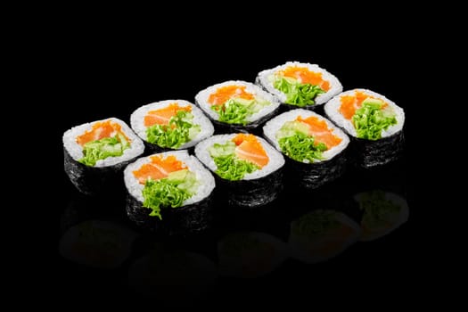 Colorful futomaki rolls with fresh salmon, tobiko, avocado, cucumber and lettuce presented on black background. Popular Japanese snack
