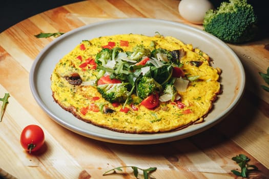 A vibrant omelet featuring tender broccoli and juicy tomatoes, served on a plate. A colorful and nutritious breakfast option.