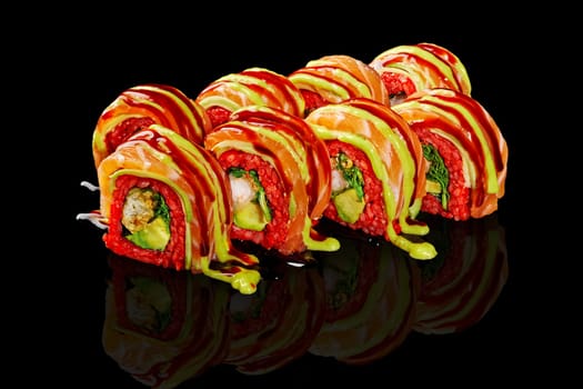 Vibrant red rice sushi rolls with tempura shrimp and avocado, topped with salmon slice and spicy sauces, presented on black reflective background. Japanese fusion cuisine