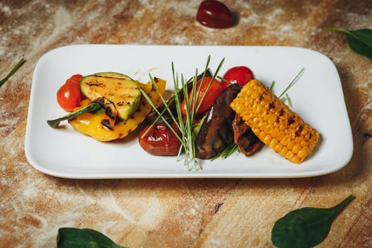 Colorful grilled vegetables and corn arranged beautifully on a white plate, showcasing a delicious and healthy meal option.