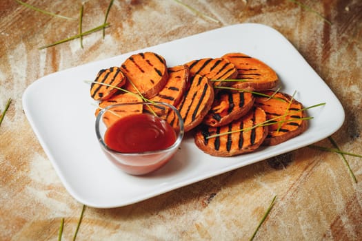 Juicy sweet potato wedges grilled to perfection, served on a plate with a generous dollop of ketchup for a flavorful and satisfying dish.