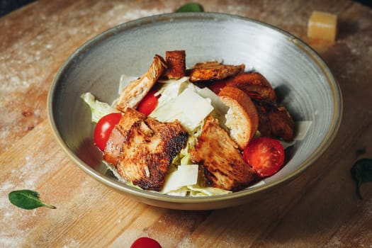 A delicious bowl filled with a colorful chicken salad placed on a rustic wooden table, ready to be enjoyed.