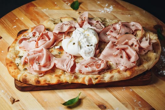 A delicious pizza topped with savory ham and gooey cheese, resting on a rustic wooden board.