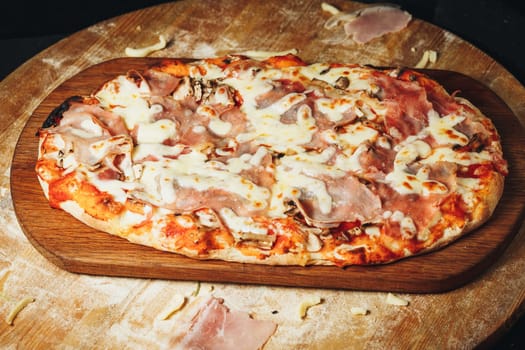 A delicious pizza topped with flavorful ham and melted cheese, presented on a rustic wooden board.