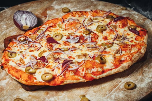 A delicious pizza topped with olives and onions, served on a rustic wooden board.