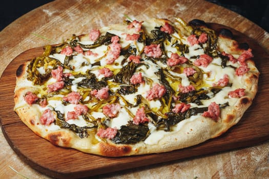 A delectable pizza topped with savory meat and fresh greens, displayed on a rustic wooden cutting board.