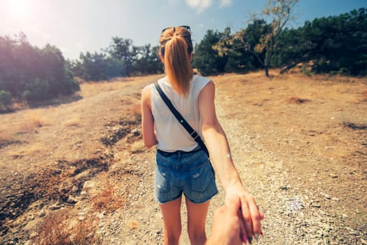 girlfriend is the hand of her boyfriend in a Hiking trip. Couple resting together. Follow me - point of view