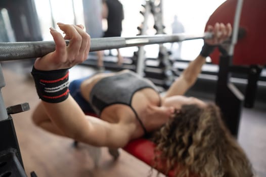 Middle aged woman doing bench press at the gym