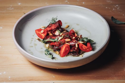 A vibrant bowl filled with juicy tomatoes and fragrant herbs rests elegantly on a rustic wooden table.