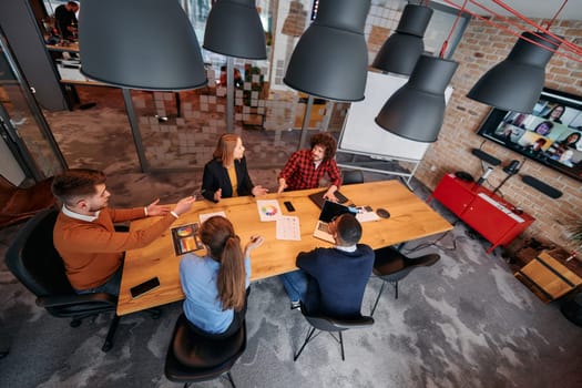 Top view of a modern startup office, a diverse team of business professionals engage in discussions on various projects and develop new business strategies, epitomizing creativity and innovation in the entrepreneurial landscape.