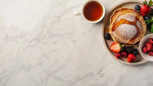 A delectable breakfast setup featuring pancakes topped with syrup and berries beside a cup of tea on a marbled surface. Banner with copy space.