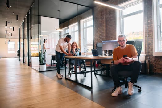 A diverse group of business professionals collaborates in a modern startup coworking center, utilizing a mix of paper-based and technological tools such as mobile phones and computers .