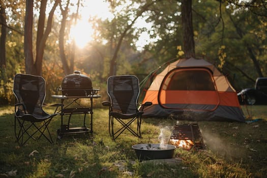 Camping outdoors with lots of sunlight. tent, chairs, a tent BBQ rack, and more.