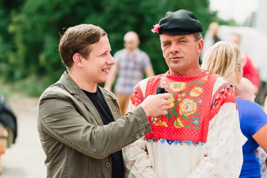 LUH, RUSSIA - AUGUST 27, 2016: reporter interviews a man at a holiday festival
