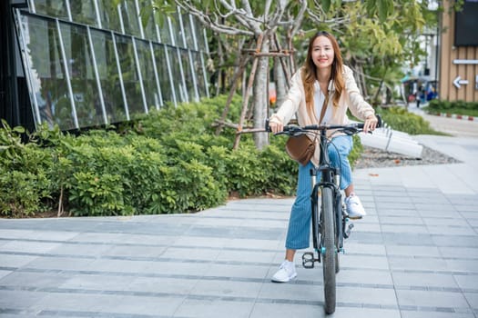 Happy Asian beautiful young woman riding bicycle on street outdoor near building city, Portrait of smiling female lifestyle using bike in summer travel means of transportation, ECO friendly