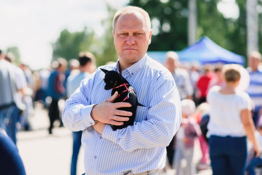 LUH, RUSSIA - AUGUST 27, 2016: man holds a small chihuahua dog in hands
