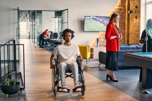 An African-American young entrepreneur in a wheelchair is surrounded by his business colleagues in a modern office setting, embodying diversity and collaboration in the workplace.