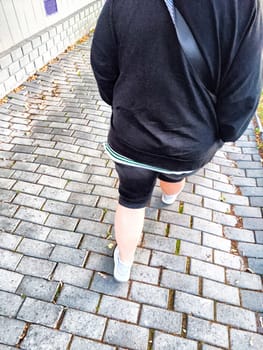 Person walking on brick-laid path in the evening. Casual Stroll on Cobblestone Sidewalk at Dusk