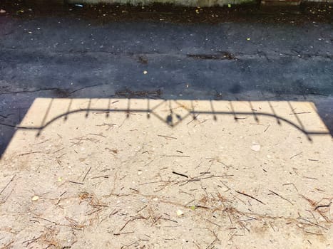 The shadow of the fence. Background, texture. Shadow of Ornate Fence Cast on Mixed Pavement at Midday. Contrast of shadow from an ornate fence