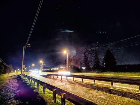 Nighttime Scene of Street With Power Lines and Transformer. Illuminated track under lantern light at night