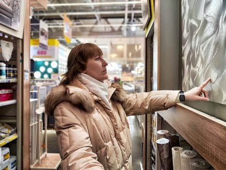 Middle-Aged Woman Shopping at a Warehouse Store. Woman browsing in large retail store aisle