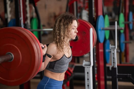 Middle-aged woman doing squats with a barbell in the gym