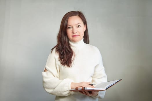 Confident middle aged Business woman in White Turtleneck with Notebook. A professional mature woman ready for meeting