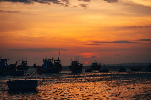 traditional Vietnamese fishing boats on the sea in the background of orange sunset