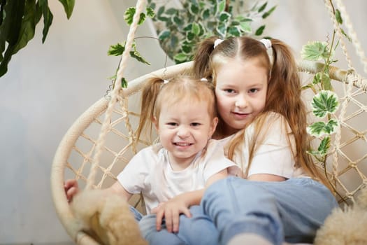 Happy time concept. Girls Sisters in chair and having fun. Female Preschooler and teenager playing and relaxing in room