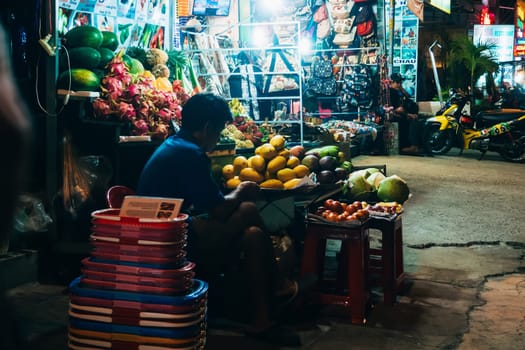 MUI NE, VIETNAM - CIRCA MARCH 2017: Fruit seller at the counter on the night street
