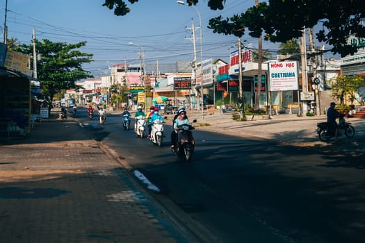 MUI NE, VIETNAM - CIRCA MARCH 2017: A lot of people riding on motorbikes on the road against the background of advertising and shops