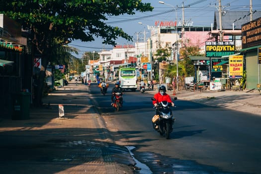 MUI NE, VIETNAM - CIRCA MARCH 2017: A lot of people riding on motorbikes on the road against the background of advertising and shops