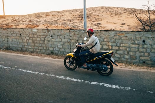 MUI NE, VIETNAM - CIRCA MARCH 2017: A man riding a motorbike on the road