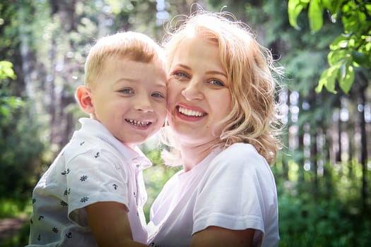 A mother and young son sharing a loving gaze among vibrant green trees