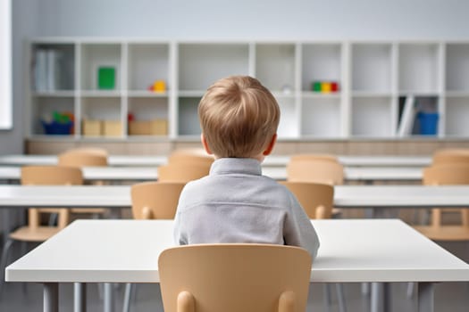 Back view of a young student sitting alone at a desk in a bright, modern classroom, perfect for educational content, school environments, and child development themes. Generative AI