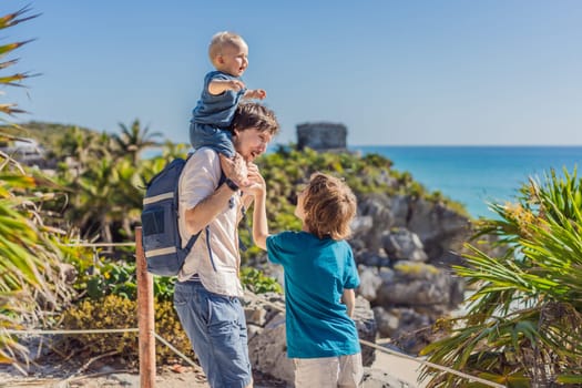 Father and two sons tourists enjoying the view Pre-Columbian Mayan walled city of Tulum, Quintana Roo, Mexico, North America, Tulum, Mexico. El Castillo - castle the Mayan city of Tulum main temple.